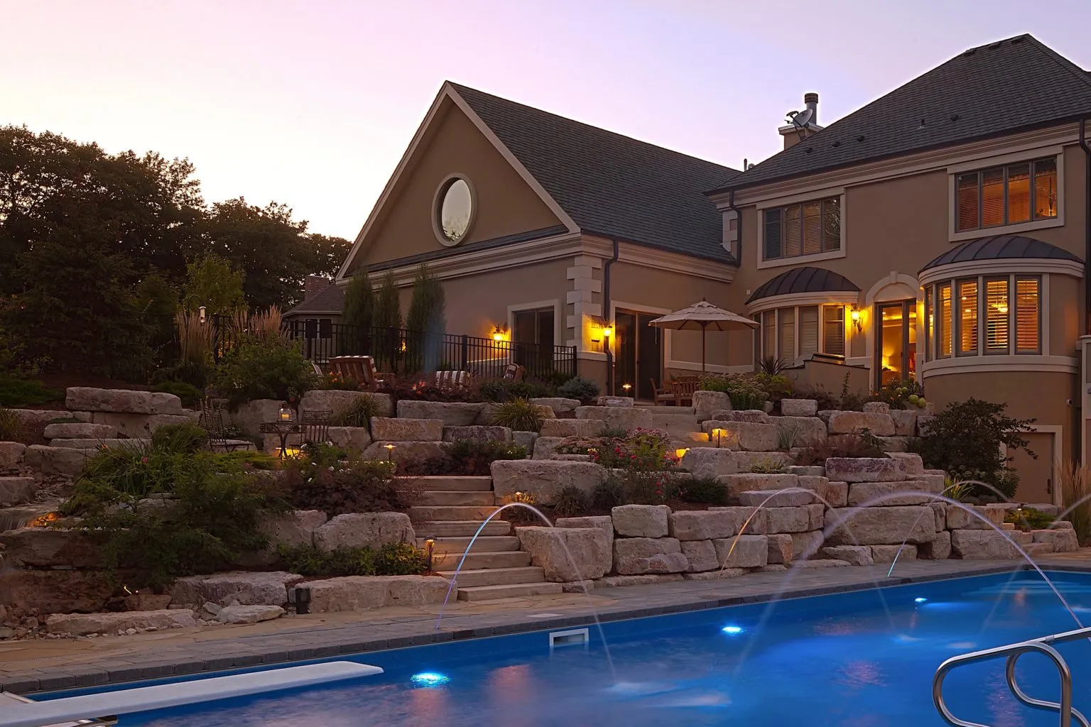 Boulder retaining wall with natural stone steps around pool